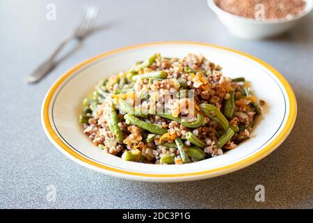 Bouillie de sarrasin avec haricots verts et carottes sur la table grise gros plan, repas végétarien sain sans gluten Banque D'Images