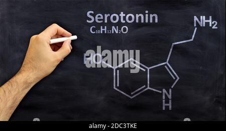 Formule chimique structurale de sérotonine, dessin à la main avec une craie sur un tableau noir, classe de chimie scolaire. Modèle d'hormone du bonheur Banque D'Images