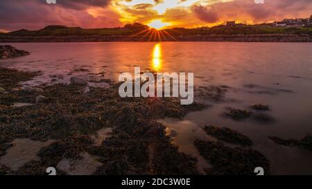 Port de l'île de Whithorn situé dans un coucher de soleil spectaculaire, eau encore et soleil, plage rocheuse, falaises Banque D'Images