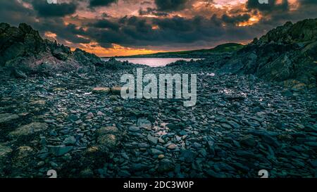 Port de l'île de Whithorn situé dans un coucher de soleil spectaculaire, eau encore et soleil, plage rocheuse, falaises Banque D'Images
