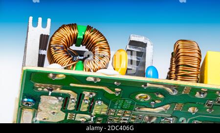 Inductances électroniques toroïdales soudées sur la carte de circuit imprimé. Enroulement du fil de cuivre sur les bobines d'induction. Composants électriques et refroidisseur en aluminium. Vue de dessous. Banque D'Images