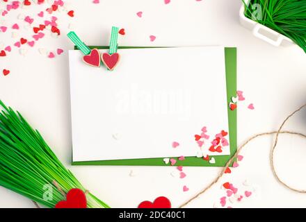 Deux enveloppes sont reliées par des épingles à linge avec des coeurs, un bouquet d'herbe de blé et de nombreux petits coeurs sur un fond clair Banque D'Images