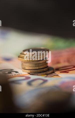 Billets en euros et pièces empilées sur un fond sombre Banque D'Images