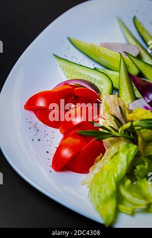 Légumes frais servis sur une assiette blanche pour en-cas au restaurant.Rouge tomates, concombres verts et salade pour la nutrition du keto diet Banque D'Images