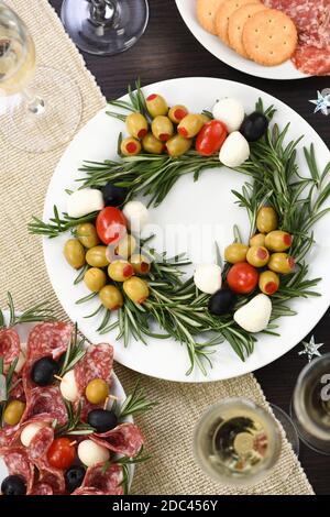 Un hors-d'œuvre de romarin farci d'olives avec de la mozzarella et des tomates cerises. Fait sous forme de couronne de Noël. Banque D'Images