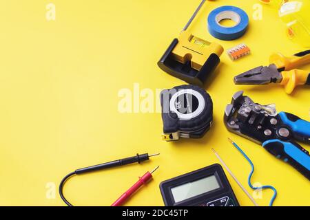 Jeu d'outils d'électricien sur fond jaune. Composition de pose à plat avec outils d'électricien et espace pour le texte fond jaune Banque D'Images