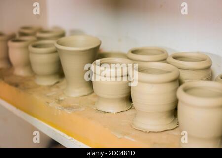 Tasses non finies sur l'étagère de l'atelier de poterie - gros plan Banque D'Images