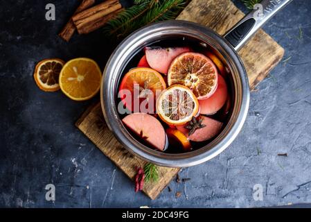 Fabrication d'alcool chaud, vin chaud à vendre à la foire de campagne. Lintoise à base de vin rouge avec agrumes et clous de girofle dans un grand pot en métal, mélangé avec une louche de soupe Banque D'Images