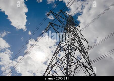 Contrastes environnementaux, grand pylône électrique en métal foncé contre un ciel bleu ciel nuageux naturel. Copiez l'espace vers le côté gauche, en plein soleil Banque D'Images