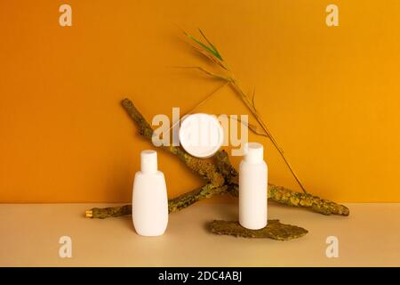 Ensemble de produits cosmétiques naturels bio écologiques dans un pot en plastique blanc, un flacon distributeur, un tube sur fond orange. Concept de soin de la peau. Vue avant, maquette. Banque D'Images