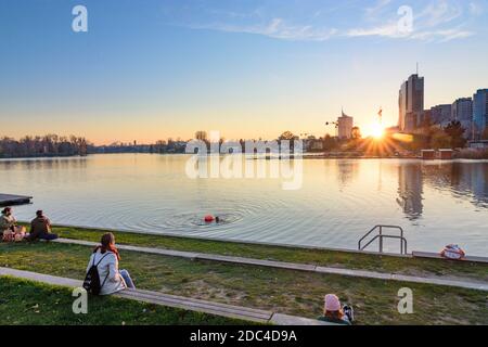 Wien, Vienne: Coucher de soleil sur le lac de l'arbalète Alte Donau (vieux Danube), bâtiments de Donaucity et Tour IZF, nageur en 22. Donaustadt, Wien, Autriche Banque D'Images