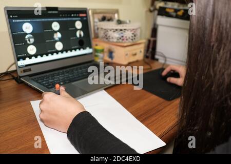 Fille gaucher tout en faisant un appel vidéo de leçon d'école intelligente sur un ordinateur portable, maladie pandémique covid-19, isolement social Banque D'Images