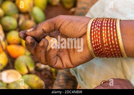 Kadenahalli, Karnataka, Inde - 3 novembre 2013 : gros plan de la main tenant la viande de noix de bétel avec tas d'entre eux dans un fond fade. Golden et Red bang Banque D'Images