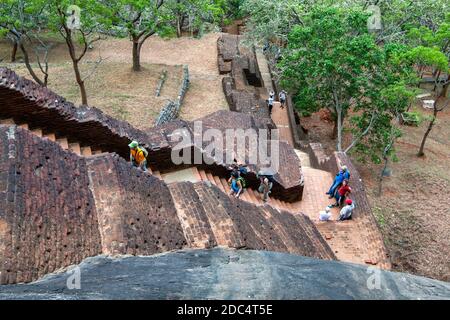 Les visiteurs de la forteresse de Sigiriya Rock au Sri Lanka grimpent l'escalier en briques des jardins royaux vers la grotte en plein air. Banque D'Images