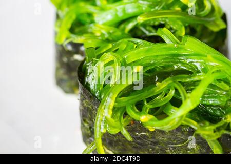 Sushi japonais maki frais avec salade de chuka arrière-plan blanc Banque D'Images