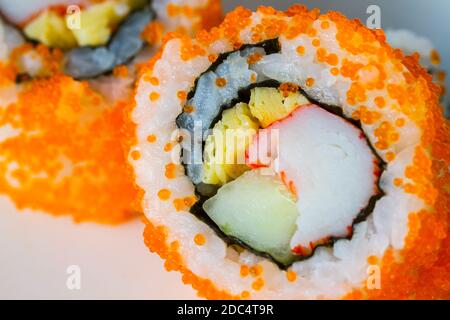 Très gros plan California Maki Sushi avec Masago - rouleau de viande de crabe, d'œuf, de concombre à l'intérieur. Masago (odeur) extérieur, zone de mise au point douce, foyer moyen Banque D'Images