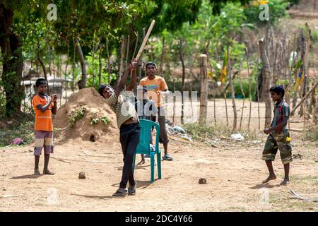 Les garçons sri lankais jouent au cricket sur un terrain poussiéreux près de la ville de Pottuvil, sur la côte est du Sri Lanka. Banque D'Images