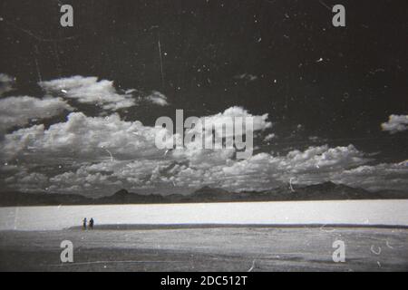 Belle photographie en noir et blanc vintage des années 1970 de deux personnes marchant le long de la plage d'été. Banque D'Images