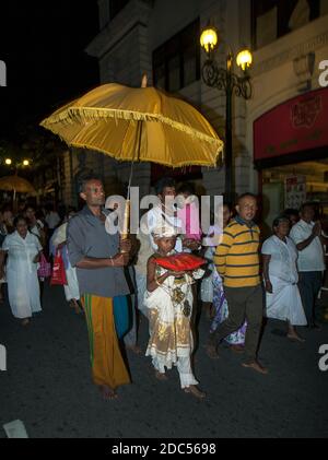 Un garçon est abrité par un parapluie lors d'une petite perahera bouddhiste (procession) qui a lieu à 4 heures du matin dans une rue à Kandy, Sri Lanka. Banque D'Images