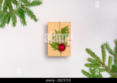 Boîte-cadeau de Noël à la main décorée de papier artisanal, branche de sapin et boule sur fond blanc. Nouvel an, jour de Thanksgiving. Pose en flanelle, vue de dessus Banque D'Images