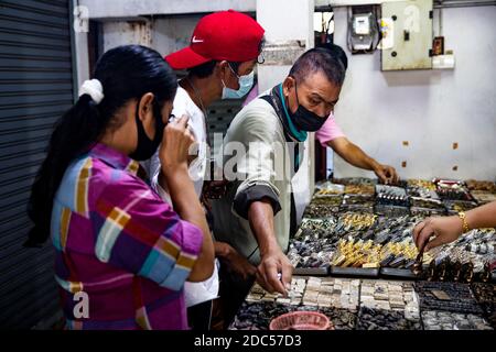 Les clients potentiels, certains utilisant la loupe, examinent de près les anciens amulettes bouddhistes dans un magasin de Tha Maharaj Pier Complex à Bangkok, en Thaïlande. Banque D'Images