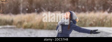 Neige hiver bonne fille asiatique avec les bras ouverts appréciant la neige chute flocons de neige porter foulard temps froid, chapeau, gants chaud veste bannière Banque D'Images