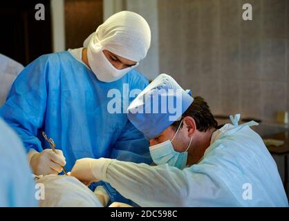 Chirurgie. Vue latérale du chirurgien effectuant l'opération, à côté de son assistant. Banque D'Images