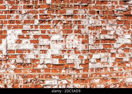 Mur de bâtiment abandonné avec des briques rouges recouvertes de stuc Banque D'Images