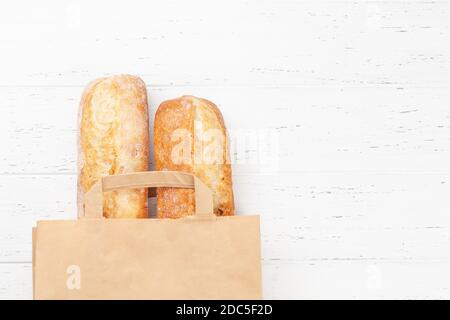 Pain de baguette dans un sac en papier. Vue de dessus du plan de travail avec espace de copie Banque D'Images