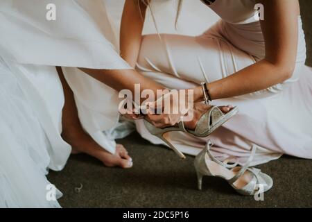 Une femme aidant la mariée à porter sa chaussure Banque D'Images