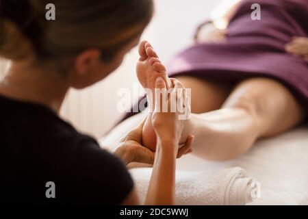 Gros plan masseuse femme massant le pied du client au spa Banque D'Images