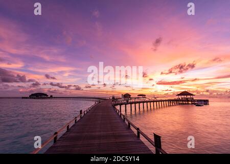 Coucher de soleil sur l'île des Maldives, luxueux complexe de villas aquatiques et jetée en bois. Magnifiques nuages de ciel et plage nature fond pour les vacances d'été Banque D'Images