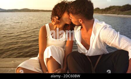 Scène romantique de race hétérosexuelle mixte couple d'amoureux embrassant Avec passion sur une jetée en bois au coucher du soleil - romantique beau et élégant jeune homme flirti Banque D'Images