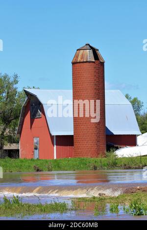 Kansas Red Barn et Silo avec des eaux d'inondation au printemps à Hutchinson Kansas USA dans le pays. Banque D'Images