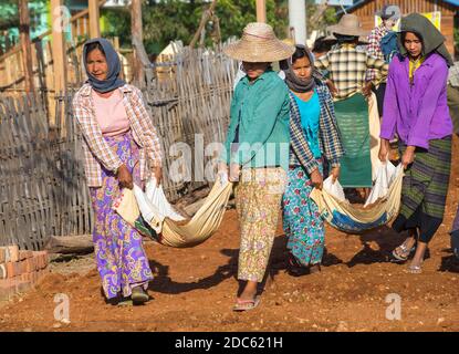 Les villageois s'engagent les travaux de construction de la route manuel West Phwar vu Village, Bagan, Myanmar (Birmanie), l'Asie en février - femmes déplacer des matériaux Banque D'Images