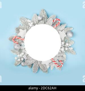 Brindilles de sapin givrées et boules décoratives de Noël arrière-plan bleu avec une carte circulaire blanche avec espace de copie pour modèle de texte plat dessus Banque D'Images