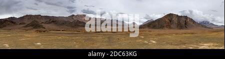 Panorama de la pluie, des nuages et des montagnes de couleur orange avec de la neige sur la route de Pamir au Tadjikistan près d'Alichur et Murghab. Banque D'Images