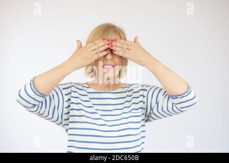 Moyenne âge belle femme portant une chemise décontractée en denim debout sur fond rose couvrant les yeux avec les mains souriantes et drôles. Concept aveugle Banque D'Images