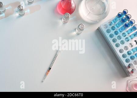 Seringue jetable sur une table dans un laboratoire pharmaceutique avec flacons et verrerie. Vue de dessus. Composition horizontale. Banque D'Images