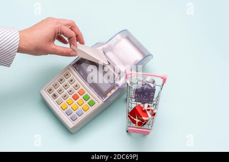 Gros plan de la main d'une femme déchirant un chèque d'une ancienne caisse à côté d'un panier avec boîtes de cadeaux sur fond bleu, vue du dessus, copie s. Banque D'Images