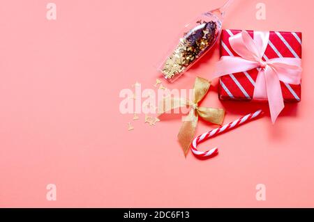 Composition de Noël avec boîtes cadeaux, chapeau de père Noël, verre de champagne et décorations sur fond rose. Vue de dessus Flat lay Banque D'Images