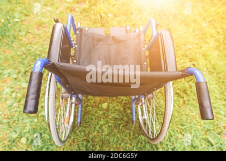 Fauteuil roulant vide debout sur l'herbe dans le parc de l'hôpital en attente de services aux patients. Président non valide pour les personnes à mobilité réduite plein air stationné dans la nature. Handicap Banque D'Images