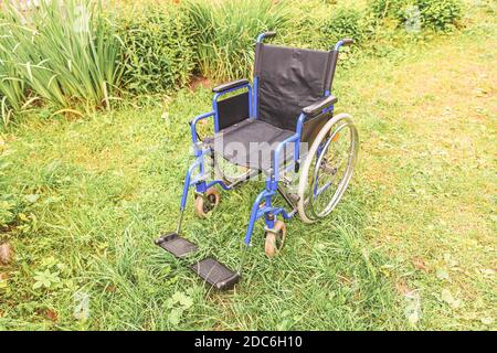 Fauteuil roulant vide debout sur l'herbe dans le parc de l'hôpital en attente de services aux patients. Président non valide pour les personnes à mobilité réduite plein air stationné dans la nature. Handicap Banque D'Images