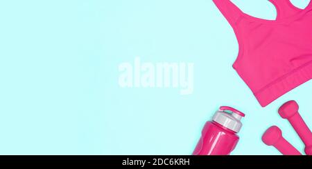 Haut de soutien-gorge sport, haltères recouvertes de néoprène, bouteille d'eau sur fond bleu large. Pose à plat. Entraînement sportif pour femmes, entraînement physique concept minimal Banque D'Images