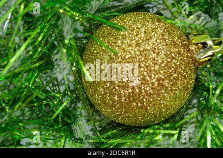 Le ballon du nouvel an d'or sur un fond vert de pluie du nouvel an. La guirlande du nouvel an Banque D'Images