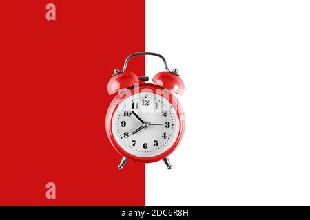 Vieux réveil rouge sur fond rouge et blanc. Montre vintage à plat créative sur fond de couleur, espace de copie dans un style minimal, modèle vide pour Banque D'Images