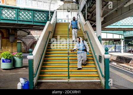 Les travailleurs en costume de protection nettoient les rails de retenue de la gare de Lewes pendant la pandémie Covid 19, à Lewes, dans l'est du Sussex, au Royaume-Uni. Banque D'Images