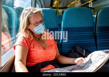 Une femme voyageur sur UN train à destination de Londres portant UN masque facial de protection pendant la pandémie Covid 19, Sussex, Royaume-Uni. Banque D'Images