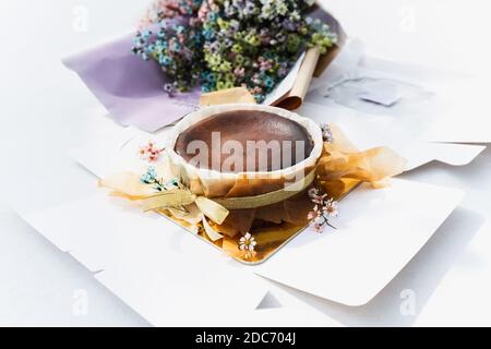 Chocolat basque cheesecake brûlé avec bouquet de fleurs sur la table. Banque D'Images