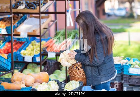 La femme de beauté choisit des légumes sur le marché des légumes Banque D'Images